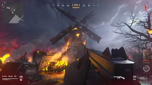 A burning windmill from the perspective of a person holidng a gun.